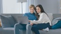 Cute Young Couple Use Laptop Computer, Have Fun, Laughs, while Sitting on the Couch in the Cozy Royalty Free Stock Photo