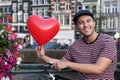 Cute young ethnic guy holding a heart-shaped balloon Royalty Free Stock Photo