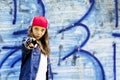 Cute young fair-haired girl teenager in a baseball cap and denim shirt on a stone wall background. Royalty Free Stock Photo