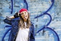 Cute young fair-haired girl teenager in a baseball cap and denim shirt on a stone wall background. Royalty Free Stock Photo