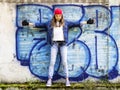 Cute young fair-haired girl teenager in a baseball cap and denim shirt on a stone wall background. Royalty Free Stock Photo