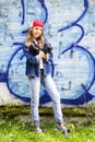 Cute young fair-haired girl teenager in a baseball cap and denim shirt on a stone wall background. Royalty Free Stock Photo