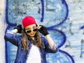 Cute young fair-haired girl teenager in a baseball cap and denim shirt on a stone wall background. Royalty Free Stock Photo