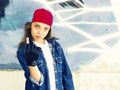 Cute young fair-haired girl teenager in a baseball cap and denim shirt on a stone wall background. Royalty Free Stock Photo