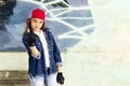 Cute young fair-haired girl teenager in a baseball cap and denim shirt on a stone wall background. Royalty Free Stock Photo