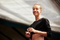 A cute young fitness girl takes out wireless headphones from a case. Attractive smiling blonde in a black suit is going Royalty Free Stock Photo