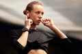 A cute young fitness girl takes out wireless headphones from a case and puts them in the ears. Attractive blonde in a Royalty Free Stock Photo