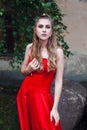 A cute young girl with blond flowing long hair and beautiful make-up, in a long red dress Royalty Free Stock Photo