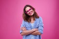 Cute young girl in checked shirt and glasses over pink