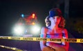 Cute young girl with curly hair and in hat standing outdoors near police line tape. Conception of crime or riot