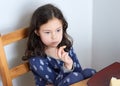 pretty young girl eating bread and butter in her pajamas at breakfast