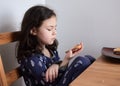 pretty young girl eating bread and butter in her pajamas at breakfast