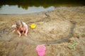 Cute young girl having fun on a sandy lake beach on warm and sunny summer day. Kid playing by the river Royalty Free Stock Photo