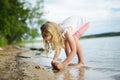 Cute young girl having fun on a sandy lake beach on warm and sunny summer day. Kid playing by the river Royalty Free Stock Photo