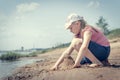 Cute young girl having fun on a sandy lake beach on warm and sunny summer day. Young girl playing by the river. Summer activities Royalty Free Stock Photo