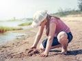Cute young girl having fun on a sandy lake beach on warm and sunny summer day. Young girl playing by the river. Summer activities Royalty Free Stock Photo