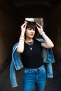 Cute young girl in jeans suit, wearing sunglasses posing in arch in city street.