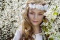 Cute young girl with long blond hair standing in a meadow in wreath of flowers, holding a bouquet of spring flowers Royalty Free Stock Photo