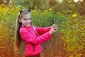 A cute young girl photographs herself in an autumn park Royalty Free Stock Photo