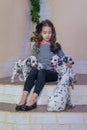 Cute young girl playing with puppies of dalmatian. Indoors. Studio portrait.