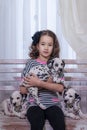 Cute young girl playing with puppies of dalmatian. Indoors. Studio portrait.