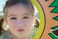 Cute young girl in ponytails, looking at camera, in between a colorful frame