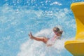 Cute young girl into pool after going down water slide. Summer holiday, adventure and happy childhood concept Royalty Free Stock Photo