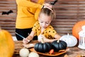 Cute young girl sitting at a table, decorating little white pumpkins. DIY Halloween concept.