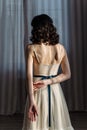 Cute young girl stands in the studio on the background of curtains. Beautiful naked back is visible. Royalty Free Stock Photo
