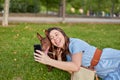 Cute young girl sticking out her tongue doing a selfie with her pharaoh dog lying on the grass in a park. Royalty Free Stock Photo