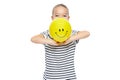 Cute young girl in stripped T-shirt holding yellow balloon with smiley face. Portrait of happy child with balloon. Royalty Free Stock Photo