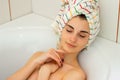 Cute young girl with a towel on head lies in the bathtub Royalty Free Stock Photo