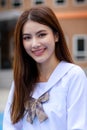 Cute and young girl wearing Japanese, Kerean style schoolgirl uniform pose to camera with fun and happy in front of school