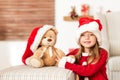 Cute young girl wearing santa hat holding her christmas present, soft toy teddy bear. Happy kid with xmas present. Royalty Free Stock Photo