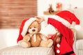 Cute young girl wearing santa hat playing with her christmas present, soft toy teddy bear. Happy kid. Royalty Free Stock Photo