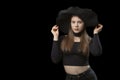 Cute young girl wears tight-fitting black top and wide-brimmed hat. Studio portrait on black background. Copy space Royalty Free Stock Photo