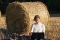 Girl in a white sweater on the background of a haystack and green forest in a field works at a laptop Royalty Free Stock Photo