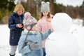 Cute young girls and their grandma building a snowman in the backyard. Cute children playing in a snow Royalty Free Stock Photo