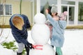 Cute young girls and their grandma building a snowman in the backyard. Cute children playing in a snow Royalty Free Stock Photo