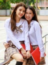 Cute and young girls wearing Japanese, Korean style schoolgirl uniform, holding books and pose to camera together with fun and