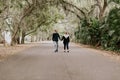 Cute Young Happy Loving Couple Walking Down an Old Abandoned Road with Mossy Oak Trees Overhanging Royalty Free Stock Photo