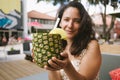 Cute young latino woman drinking cocktail from fresh pineapple ananas during summer with summer outfit at a lounge bar outdoor Royalty Free Stock Photo