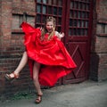 A cute young laughing girl with blond flowing long hair and beautiful make-up, in a long red dress Royalty Free Stock Photo