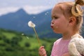 Cute young little girl blowing dandelion in sunny day. Royalty Free Stock Photo