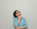 cute young man with glasses touching chin, looking up and dreaming Royalty Free Stock Photo