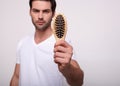 Cute young man holds a hairbrush directly to the camera