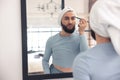 Cute young man pencilling brows in the bathroom