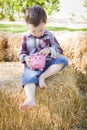 Cute Young Mixed Race Boy Putting Coins Into Piggy Bank Royalty Free Stock Photo