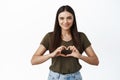 Cute young romantic woman showing heart sign, I love like you gesture, standing over white background