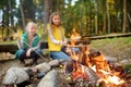 Cute young sisters roasting hotdogs on sticks at bonfire. Children having fun at camp fire. Camping with kids in fall forest Royalty Free Stock Photo